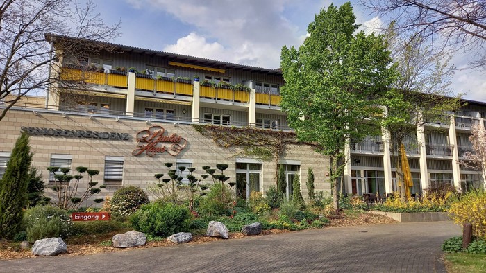 Das Bild zeigt ein modernes Gebäude mit Garten und Parkplatz.