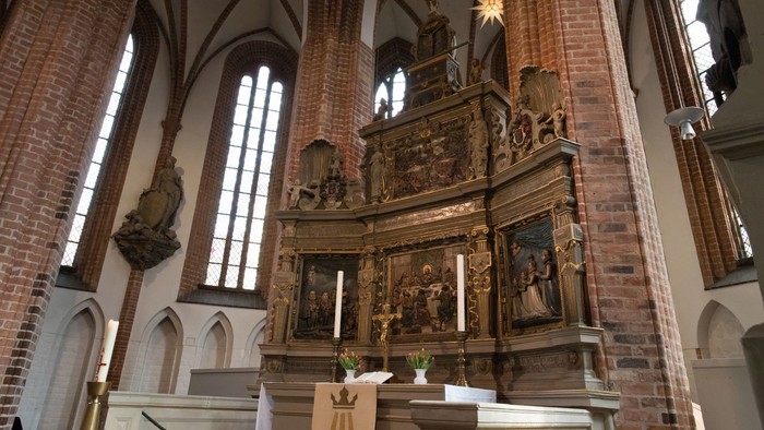 Innenraum einer gotischen Kirche mit Altarraum und hohen Fenstern