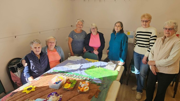 Group of women gathered around a table with craft supplies.
