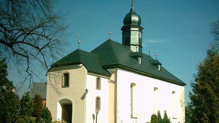 Kleine Kirche mit grünem Dach und Turm auf Hügel