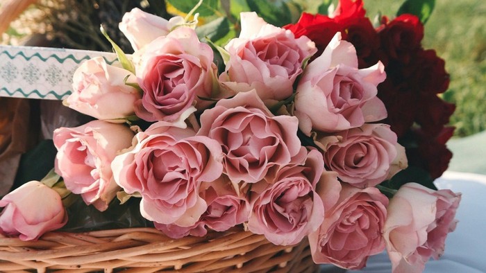 Ein Korb mit rosa und roten Rosen auf einem Tisch im Freien