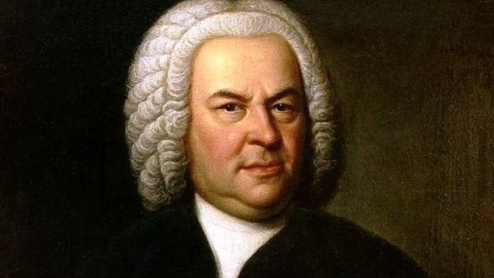 Ein Mann mit Perücke, es ist Johann Sebastian Bch, hält ein Noten-Schriftstück in der Hand