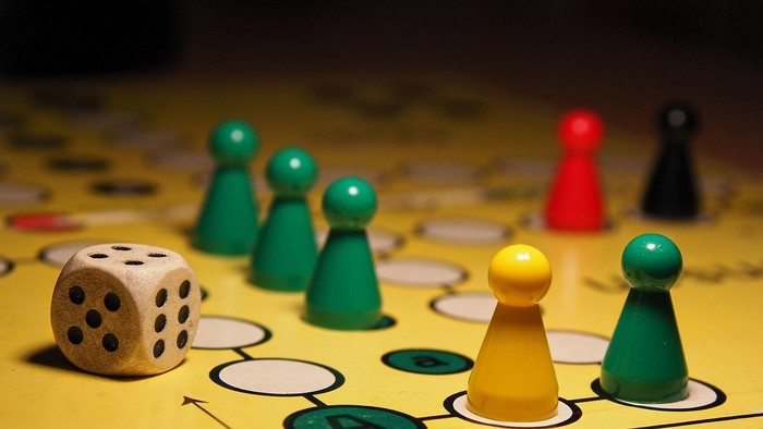 Spielfiguren und Würfel auf Mensch-ärgere-dich-nicht Spielbrett