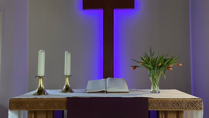 Ein Altar mit Kreuz, Kerzen und Blumen.
