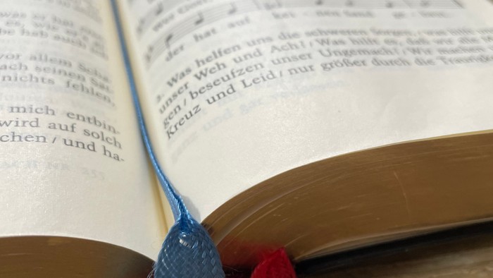 Offenes Buch mit Lesezeichen aus Stoff auf Holzoberfläche