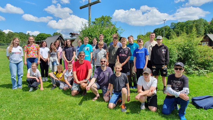 Gruppe von Personen, die im Freien auf einer grasbewachsenen Fläche posieren.