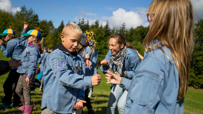 Børn leger udendørs med en frisbee.