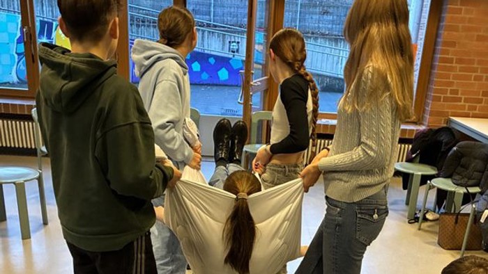 Jugendliche tragen eine Jugendliche in einer Decke