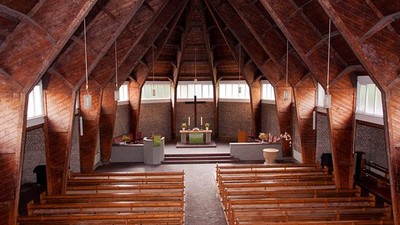 Innenraum einer Kirche mit Holzstühlen und hohem Gewölbe
