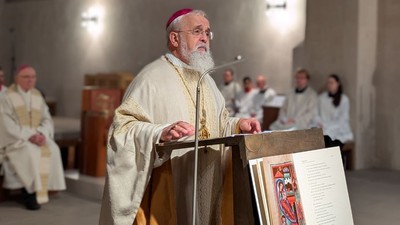 Ein Bischof hält einen Gottesdienst ab und spricht von einem Pult in einer Kirche mit Geistlichen und Gemeinde.