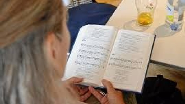 En person læser et bog på en bord med en glas og en pose.