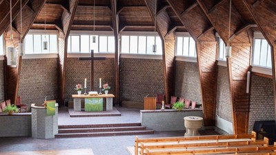 Ein moderner Wohnraum mit hohen Decken und großen Fenstern, eingerichtet mit Holz und grünen Akzenten.