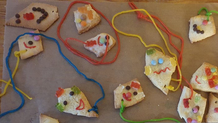 Bunte Kekskäse-Mäuse mit Süßigkeiten-Dekoration auf Backpapier.