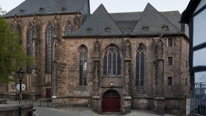 Alte Steinkirche mit Rundbogenfenstern und Holztür.
