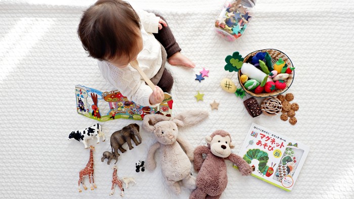 A child playing with toys and books on a rug