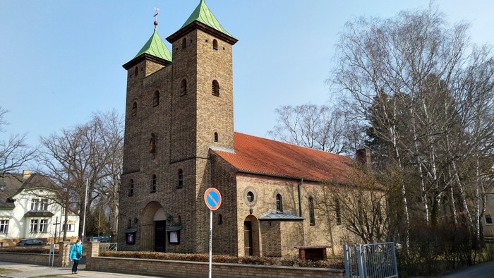 Alte Kirche mit zwei Türmen und rotem Dach an der Straße