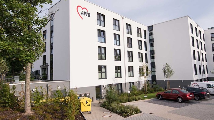 Modernes Bürogebäude mit Parkplatz und Bäumen.