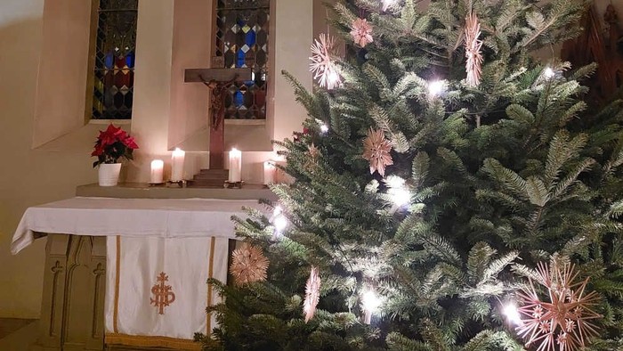 Weihnachtsbaum in der Kirche mit Kerzen und Kreuz