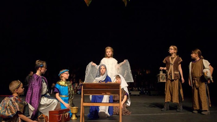 Kinder führen eine Weihnachtskrippe auf der Bühne auf.