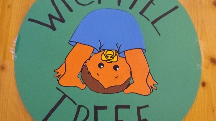 Ein Cartoon-Mädchen mit orangefarbenen Haaren und blauer Bluse, das auf dem Kopf steht, ist auf einem grünen Kreis mit dem Text 