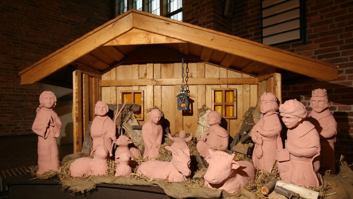 Eine Krippe mit mehreren Figuren, darunter Maria, Josef und das Jesuskind, in einer Holthütte.