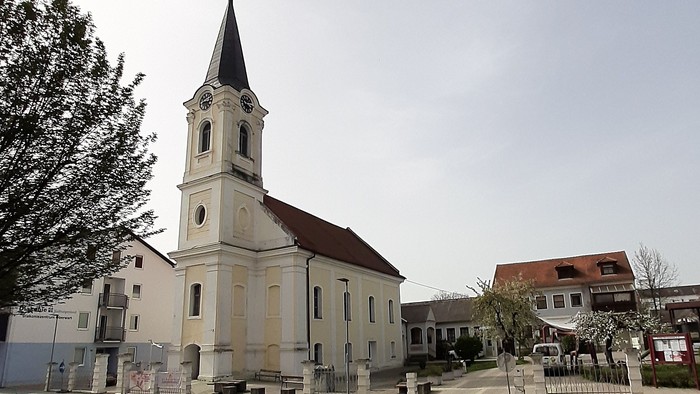 Kirchengebäude mit hohem Turm und Uhr in kleiner Stadt