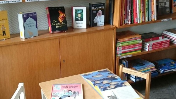 Kleiner Tisch mit zwei Stühlen vor Bücherregalen