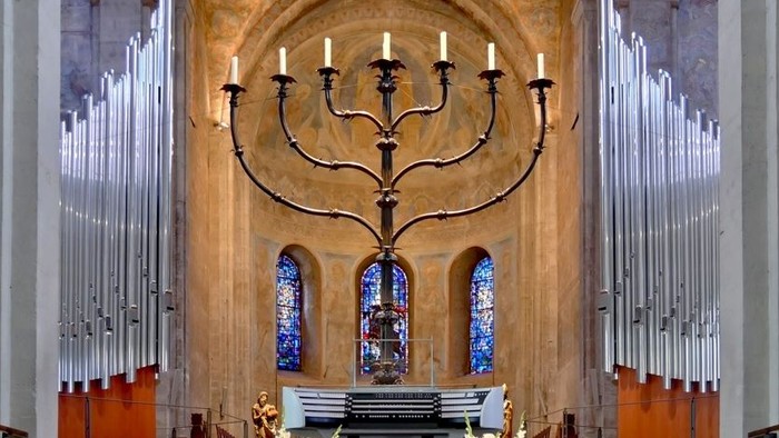 Innenraum einer Kirche mit großem Leuchter und farbenfrohen Fenstern