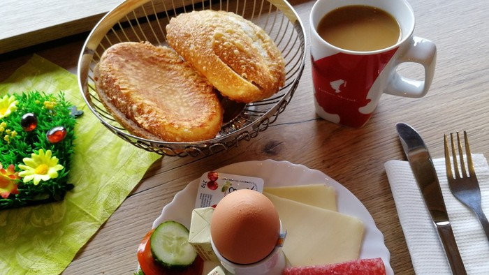 Frühstück mit Brötchen, Kaffee, Ei, Wurst und Gemüse