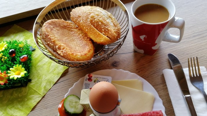 Frühstück mit Brötchen, Kaffee, Ei, Wurst und Gemüse