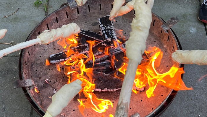 Person kocht Marshmallows über Feuer.