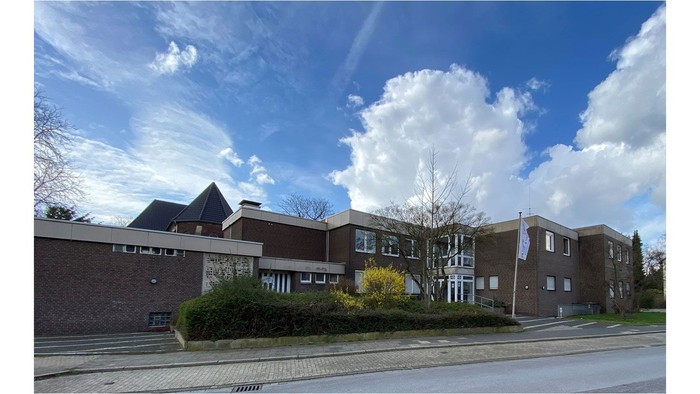 Moderne Wohngebäude mit großen Fenstern und einem klaren blauen Himmel mit weißen Wolken.