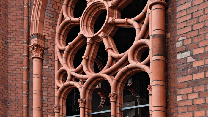 Das Bild zeigt ein großes, verziertes Fenster an einem Ziegelgebäude.