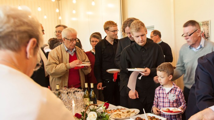 Et livligt arrangement, hvor folk forsyner sig selv med mad og drikke ved et buffet.