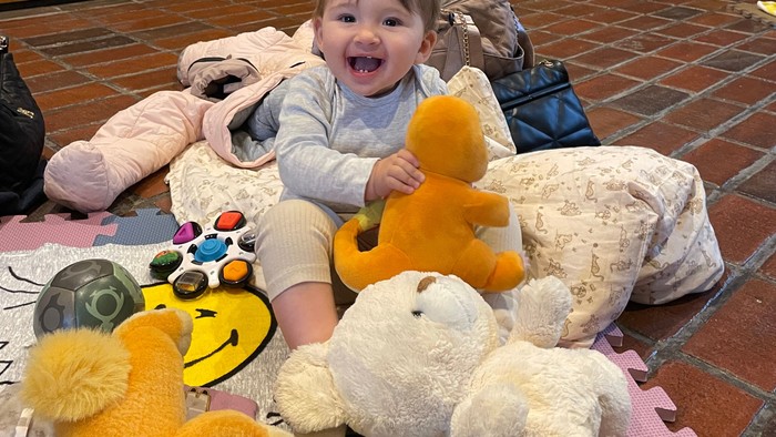 Barn sidder med bamser på legetæppe.