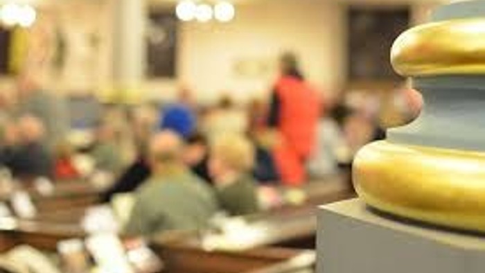 A lecture hall with students seated and a professor at the front.