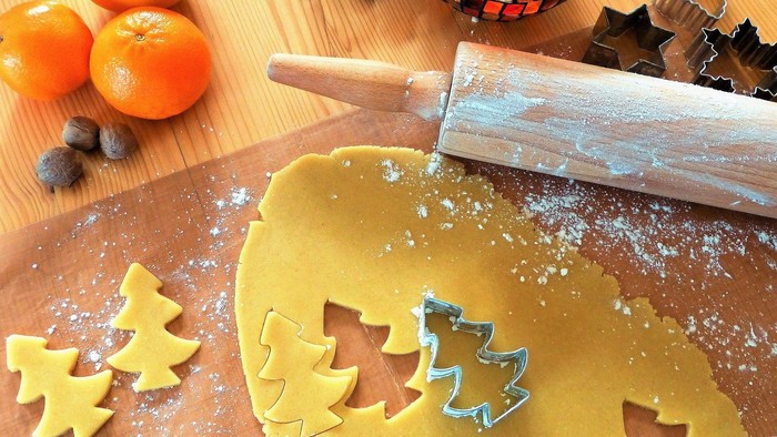 Teig wird mit Ausstechern und Nockenwalze bearbeitet, Orangen und Nüsse daneben