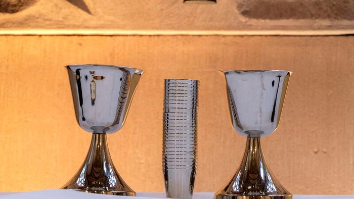 Zwei silberne Kelche und eine Schriftrolle auf einem Tisch