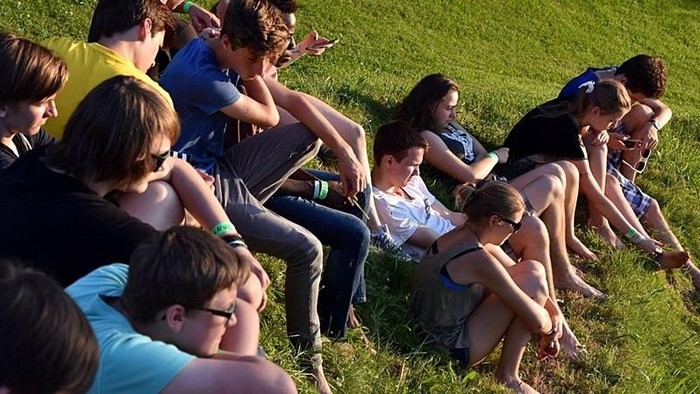 Eine Gruppe von Menschen sitzt im Gras und unterhält sich.