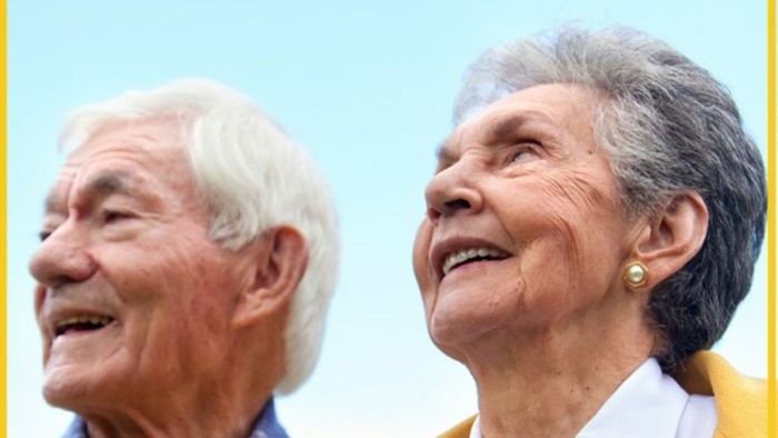 Ein älteres Paar lacht fröhlich unter einem blauen Himmel