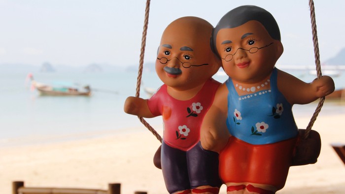 Zwei bemalte Figuren sitzen auf einem Schaukel am Strand