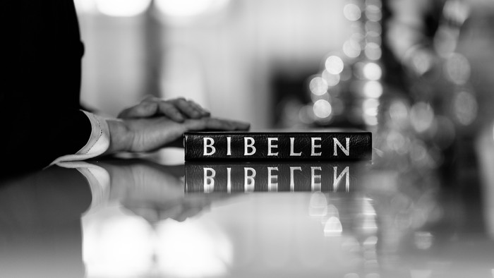 Hånd holder en bibel med titlen 