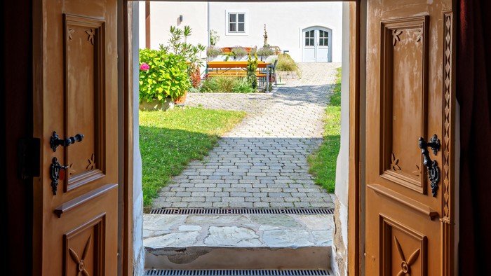Offene hölzerne Haustüren geben den Blick auf einen charmanten Gartenweg und einen üppigen Außenhof frei.