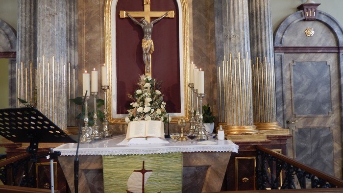 In der Kirche: Altar mit Kruzifix, Kerzen, Blumen und Musiknotenständer