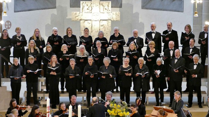 Ein Chor und ein Orchester treten in einer Kirche auf.