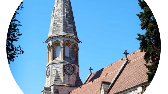 Kirketårn med klokke og kryds på et blødt blå himmel