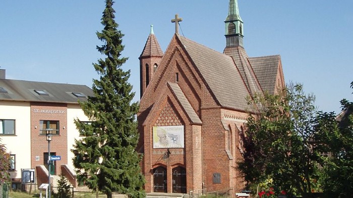 Kirchengelände mit Kopfsteinpflasterweg und Bäumen