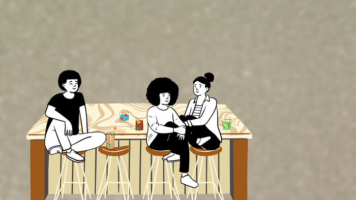 Drei Personen sitzen an einem Tisch und trinken Getränke