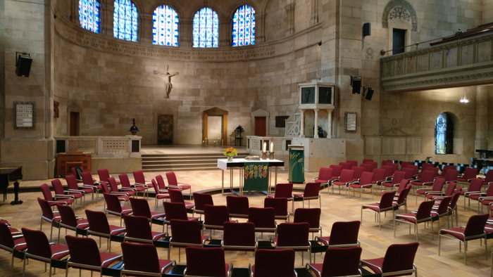 Große Kirche mit vielen Stühlen und hohen Fenstern