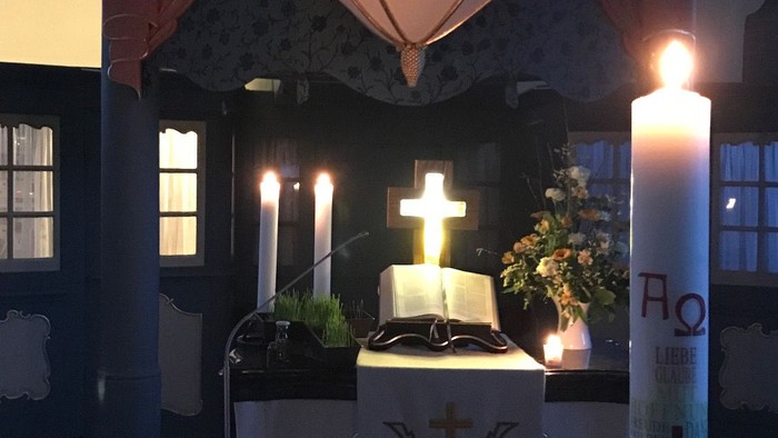 Altar in der Kirche mit brennenden Kerzen und Kreuz